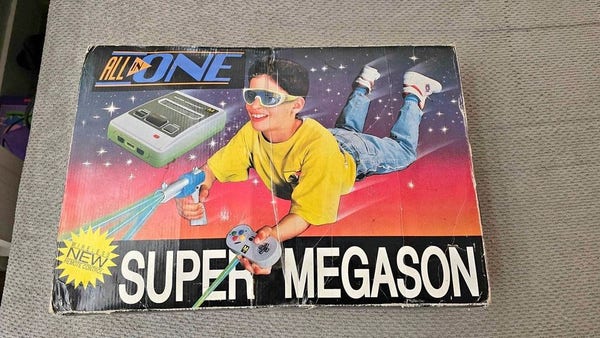 A Super Megason console box, showing a kid wearing futuristic sunglasses firing a light phaser featuring Geordi LaForge's beam-splitting technology. The other hand holds a SNES-like controller at an impossible angle. The kid has never seen a video game in their life.