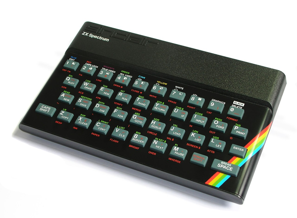 Photo of the The Sinclair ZX Spectrum keyboard on a white background. The keyboard contains letters in the standardy QWERTY layout with a row of numbers above. They keys are gray with white symbols and function names in red below.

Above the keys is an embossed lowercased name of the company, Sinclair, and below the name of the computer, ZX Spectrum, printed in smaller, white letters.

A rainbow streak wraps around one if its round edges.