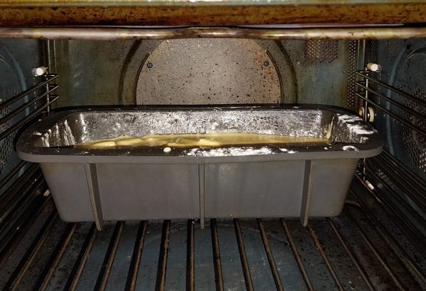 Moule à cake en silicone gris dans le four avec une pâte en train de cuire.