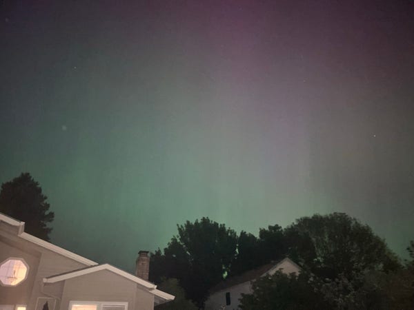 Night sky with subtle aurora lights above suburban houses.