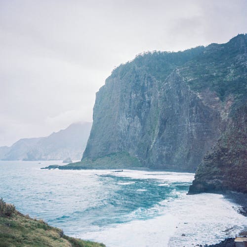 Photo of the cliffs above the ocean. The ocean is agitated, you can see the waves, and in the background there is an approaching storm.