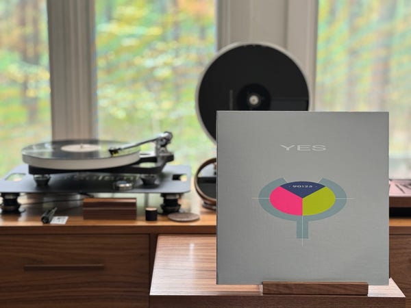Yes - 90125 Album cover.

Grey background, with a sort of rounded, split “Y” with three pie slices in the middle. Left is pink, right is yellow-green, top is navy blue, with “90125” in it.

The black LP plays on a Rega turntable to the left.