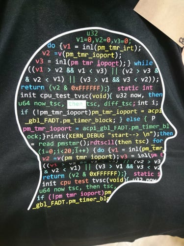 Picture of a TShirt printed with the outline of a head, filled with colorful sourcecode, apparently extracted from the Linux kernel