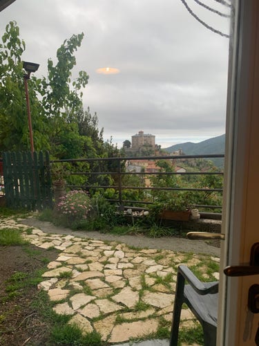 Vista dalla finestra di casa giardinetto colline verdi borgo castello e mare