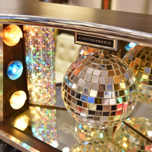 A close-up of a Morse Electrophonic, a retro-futuristic stereo console that looks slightly like a drinks cabinet and features disco lights and a mirrorball in the centre, with desirable wood cladding.