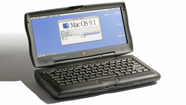 A picture of a small but appealingly chunky netbook style laptop, that looks suspiciously like a PowerBook G3 but smaller, cuter, and more trackpad-integrated-with-buttony. It's sitting on a white background, and has what appears to be a small 2.35:1 ratio screen, running Mac OS 9. It has the same delicious touchable curves as the original PowerBook G3.