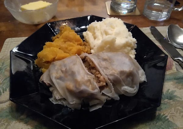 A plate has orange pile of squash, which like a lot like turnip, a pile of creamy white potatoes, and a wrapped item, sliced open that looks vaguely like a haggis in a sheep's lungs but it's really just a rice paper wrapper around a haggis mixture.