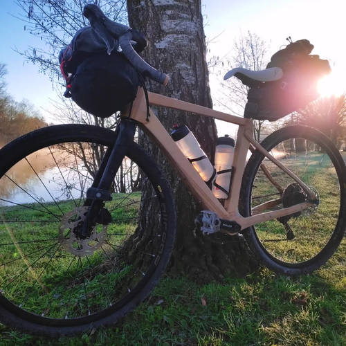 
Vélo gravel dont le cadre est en bois clair. 