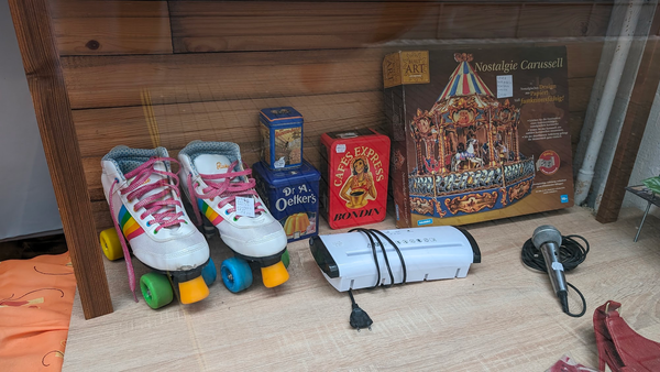 Schaufenster Auslage/ Links weisse Roller-Skates Schuhe, daneben mehrere Blechboxen und das besagte Nostalgie Carussell