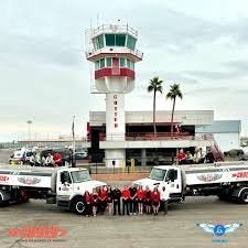 Image of the control tower outside cutter aviation in Phoenix, Az with company staff posing for a photograph in the foreground. 