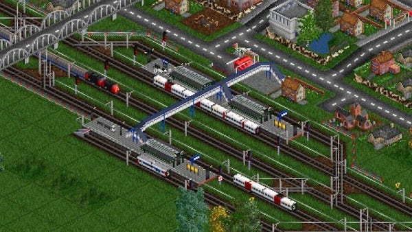 A bird's eye view of a station where several suburban or freight trains are approaching or parked, overlooked by a footbridge and a bridge. Near the station a road network and suburban dwellings. The graphics are a bit pixelated considering the age of the game and the close-up.

Open Transport Tycoon is a libre, multi-platform, single-player / multi-player (up to 255) business simulation game, based and compatible (but autonomous & enhanced) with the Transport Tycoon Deluxe game (1994). The player builds his transport network (trucks, buses, trains, planes & ships) to transport passengers and freight, with the goal of being as profitable as possible. The dividends received by these transports can be reinvested in the extension of the network or the acquisition of vehicles. A mature and actively maintained project.