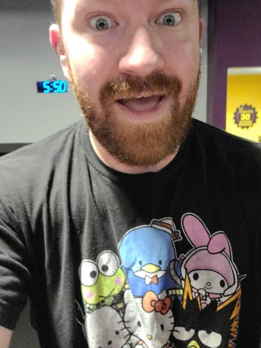 Selfie of a balding, bearded white man in black t-shirt with various Sanrio characters (Hello Kitty, Badtz Maru, My Melody, etc) all dressed as My Hero Academia characters on the center. The man is clearly sweating and elevated with the time of 05:50 visible on a digital clock in the background.