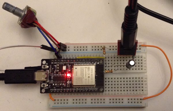 Photo of a cheap ESP32-WROOM-32D DevKit on a solderless breadboard with some passive circuitry linking it to a TRS socket and a potentiometer plugged into one of the IO connections.