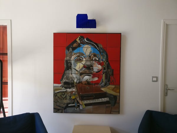 Photo d'un tableau dans un hall, c'est un portrait de Dali façon Dali (mais pas de Dali), qui est divisé en 30 carreaux de céramique.