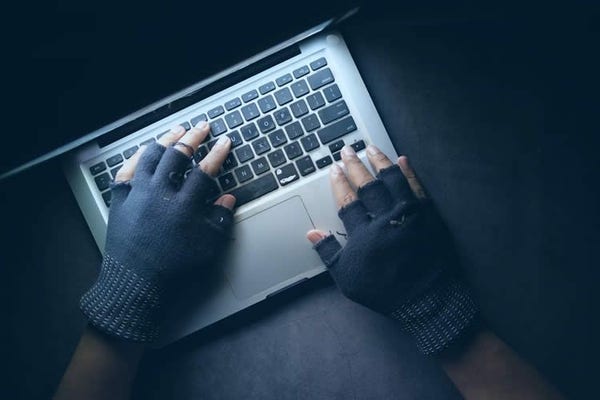 Man wearing cut off gloves using a MacBook computer