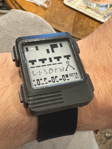 Digital wristwatch with a unique pixelated display design, worn on a person's wrist.