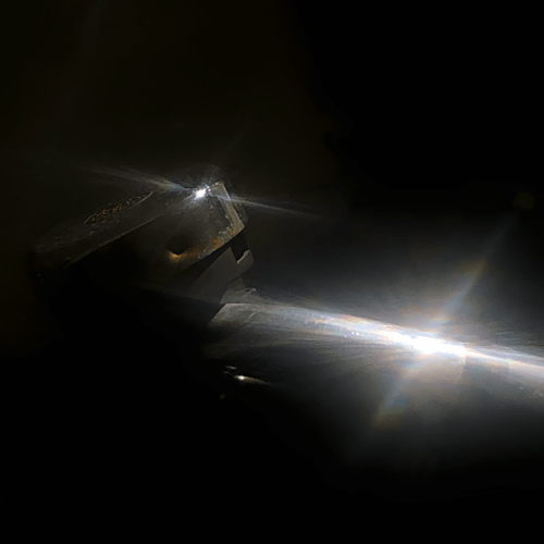 A very dark colour photo with bike bell on the left and a portion of the handlebars on the right. A bright light cast on both objects creates an atmospheric twinkle.