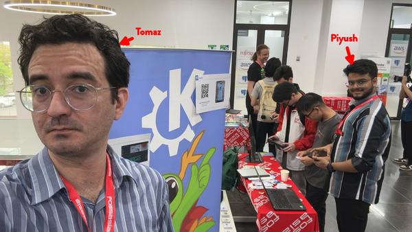 A photo in the exhibition hall at FOSSAsia 2024. In the foreground we see Tomaz, who is taking the selfies, and in the background we see Piyush, who is attending the KDE booth.