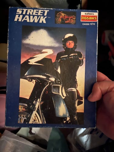 Photo of a Street Hawk jigsaw puzzle in its box. The puzzle is a photo of a guy in black motorbike leathers and helmet, sitting astride a badass looking ‘80s motorbike.

However, as a cop we all know he’s a bastard. 