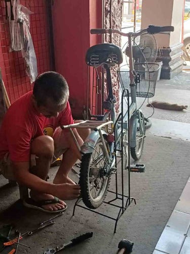 Photo of a bike mechanic installing new tires on an old folding bicycle