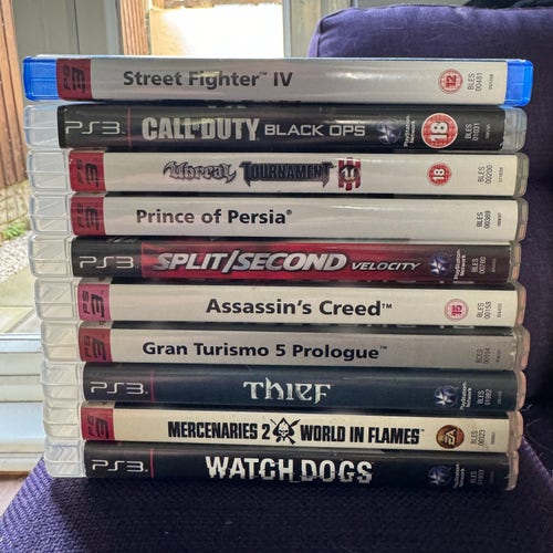 10 PS3 games laid horizontally on a sofa arm. Top to bottom:

Street Fighter IV
Call of Duty: Black Ops
Unreal Tournament III
Prince of Persia
Split/Second
Assassin’s Creed
Gran Turismo 5 Prologue
Thief
Mercenaries 2
Watch Dogs
