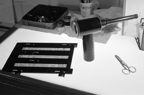 Black and white photo of a light table with various film scanning bric-a-brac. 