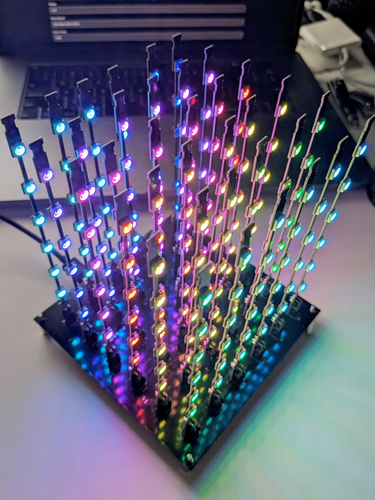 Photo of the assembled L3D cube being driven by the PixelBlaze. The frosted acrylic cover has not yet been assembled.
A grid of 6x6 thin LED strip PCBs stick out vertically from the base PCB. Each of the thin LED strip PCBs has 6 RGB LEDs. The strip PCBs connect to the base PCB with a 90 degree 2x2 pin header. The horizontal distance between the strips match the vertical distance between the LEDs.