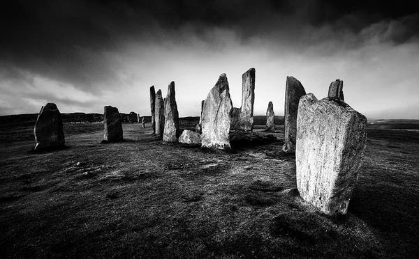 Black and white photo of the standing stones forming the circles and alignments at Callanish, on the Isle of Lewis.