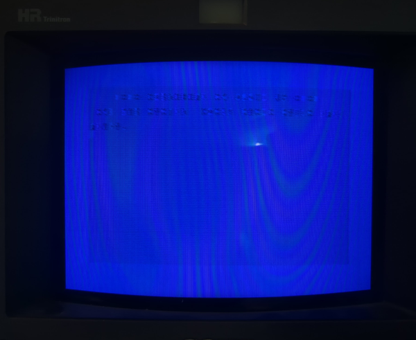 A CRT monitor showing a defective C64 power up screen: You can recognize the color scheme, but all the characters are only hard to discern shadows.