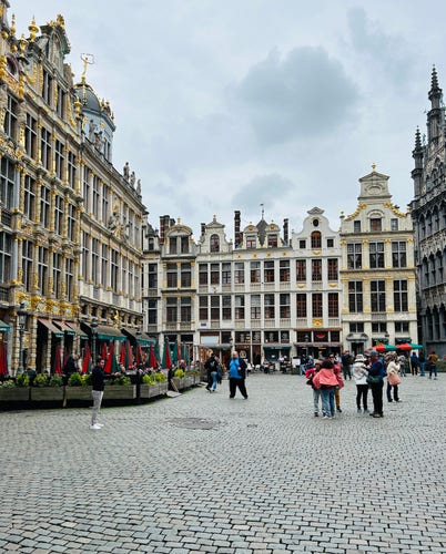 Grand Place in Brussels with ornate historical buildings and people walking on the cobblestone square.