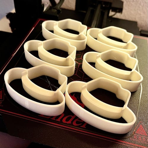 6 cookie cutters in the firm of the Red Hat logo on the printed of my 3D printer. 