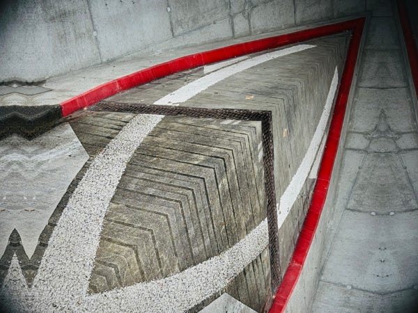 Concrete ramp with red and white hazard marking leading down to a parking garage.