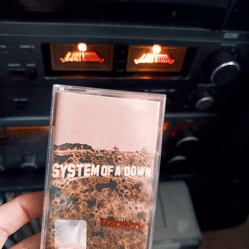 Zdjęcie albumu, wydanym na kasecie, Toxicity grupy System of a Down, na tle kaseciak Unitra ZRK M1908 oraz amplitunera Unitra M9115