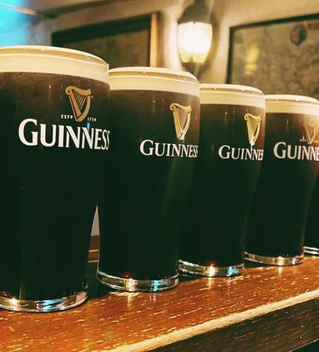 4 glasses of Guinness (Irish dark beer) on a wooden pub counter