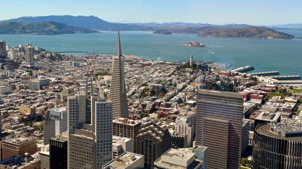 Aerial view of North part of downtown San Francisco. Buildings in the foreground include TransAmerica building. We also see the blue green water of the bay and in the distance is Alcatraz 
