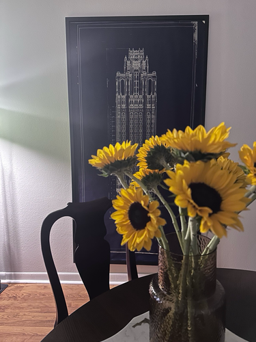 Sunflowers on dinning room table with poster of Tribune Tower on back wall. 