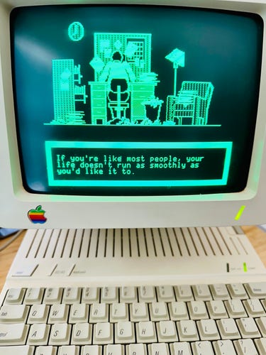 Apple IIc running Apple’s tutorial app. It shows a scene of a messy desk without someone franctically working on it.

Captions says:
if you’re like most people, your life doesn’t run as smoothly as you’d like it to.