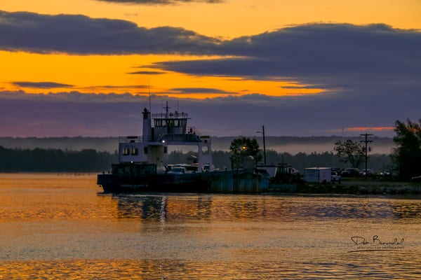 Early morning view of a car ferry at Sugar Island, Sault Ste. Marie, picking up vehicles against a backdrop of a vibrant sunrise and misty woodlands. Image at:  https://beautifulsunphotography.com/featured/sugar-island-sunrise-deb-beausoleil.html See more art & blog at: https://beautifulsunphotography.com/ https://debbeautifulsunphotography.com/ https://www.zazzle.com/store/beautifulsun_designs https://debbeausoleil.com