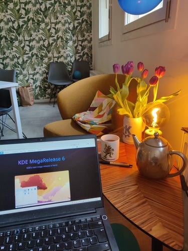 Picture of my laptop showing the kde megarelease 6 announcement, a old kde tea cup with tea and a kde beer mug with flowers 