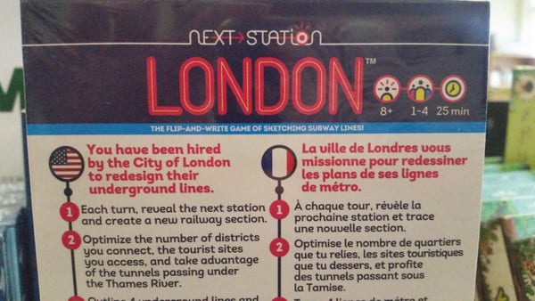 The back of a packaged box "next station" "London"

Two columns, the first in English with an american flag and the second a French flag with the description in French.