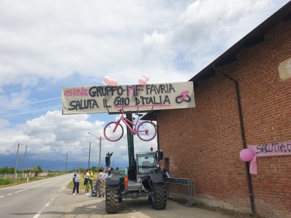 Photo d'un panneau ecrit en italien, qui salut le Giro d'Italia avec un vélo rose suspendu
