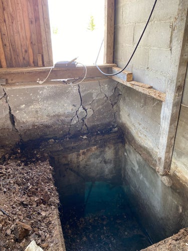 A 1m by 1.5m by 1.5m hole in the floor. The hole has concrete walls and floor. There's 10cm of water and leaves at the bottom