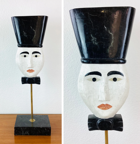 vintage 80s bric-à-brac... a stone mime like mask with high top hair, like kid n play... or is that a black top hat?

It's creepy. 