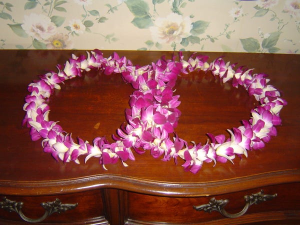 two white and pink flower garlands arranged in a lying figure eight, placed on brown antique furniture 