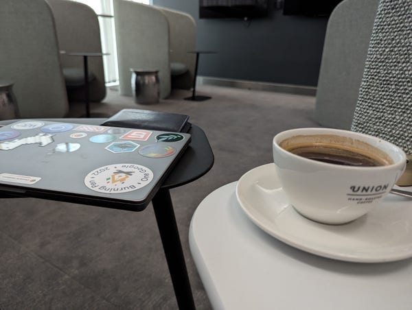 Coffee and a laptop in a work booth in an airport lounge.