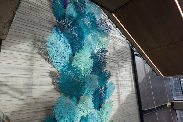 Xylem Arbor sculpture looking at the sea fan inspired region with large bent metal coral like panels protruding from the wall in turquoise and blue colors