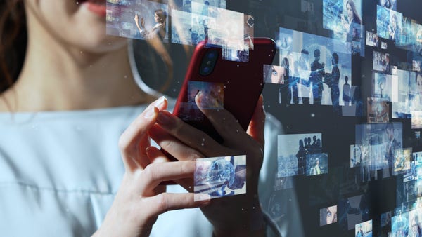 Stock image from the workshop announcement. Woman, face partially obscured, reading something on a red smartphone as a wall of glowing, non-descript images drifts by in the foreground.