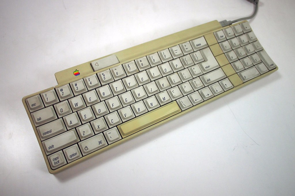 A picture from the internet showing a picture of the "Apple Desktop Bus keyboard", colloquially known as the Apple IIgs keyboard. Of note are the VERY slim bezels along most of the edges of the keyboard; that excludes the top part that houses the ADB ports, power button, and controller chip in the PCB.