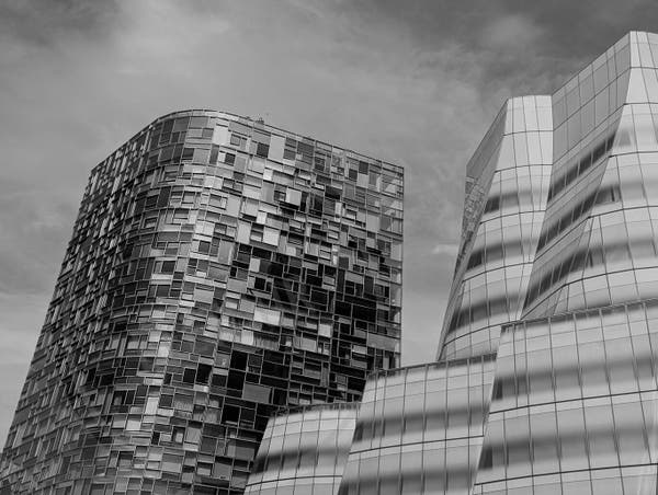 Black and white photo of two buildings standing tall with a patch of cloud passing by. It was captured in New York City with a Google Pixel 6 smartphone