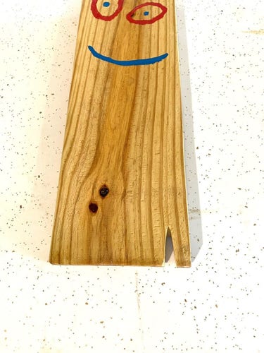 A plank of wood with a smiley face drawn on it